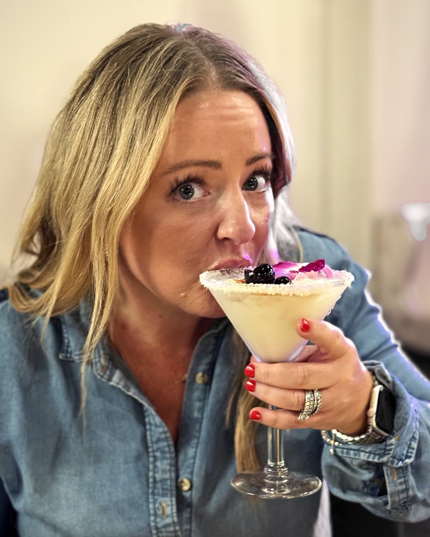 Katy sipping a coconut martini, eyebrows raised at the camera